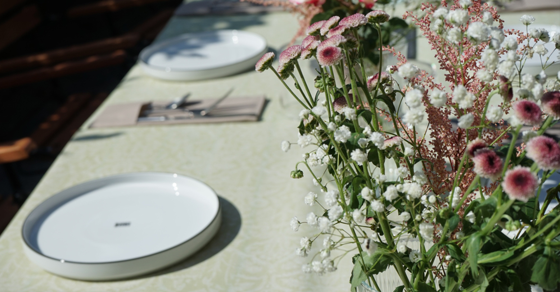 Frühlingshaft gedeckter Tisch mit zarten Blumenarrangements im Freien – Frankfurter Haus.